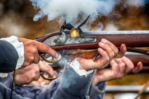 Man in revolutionary war attire firing a musket